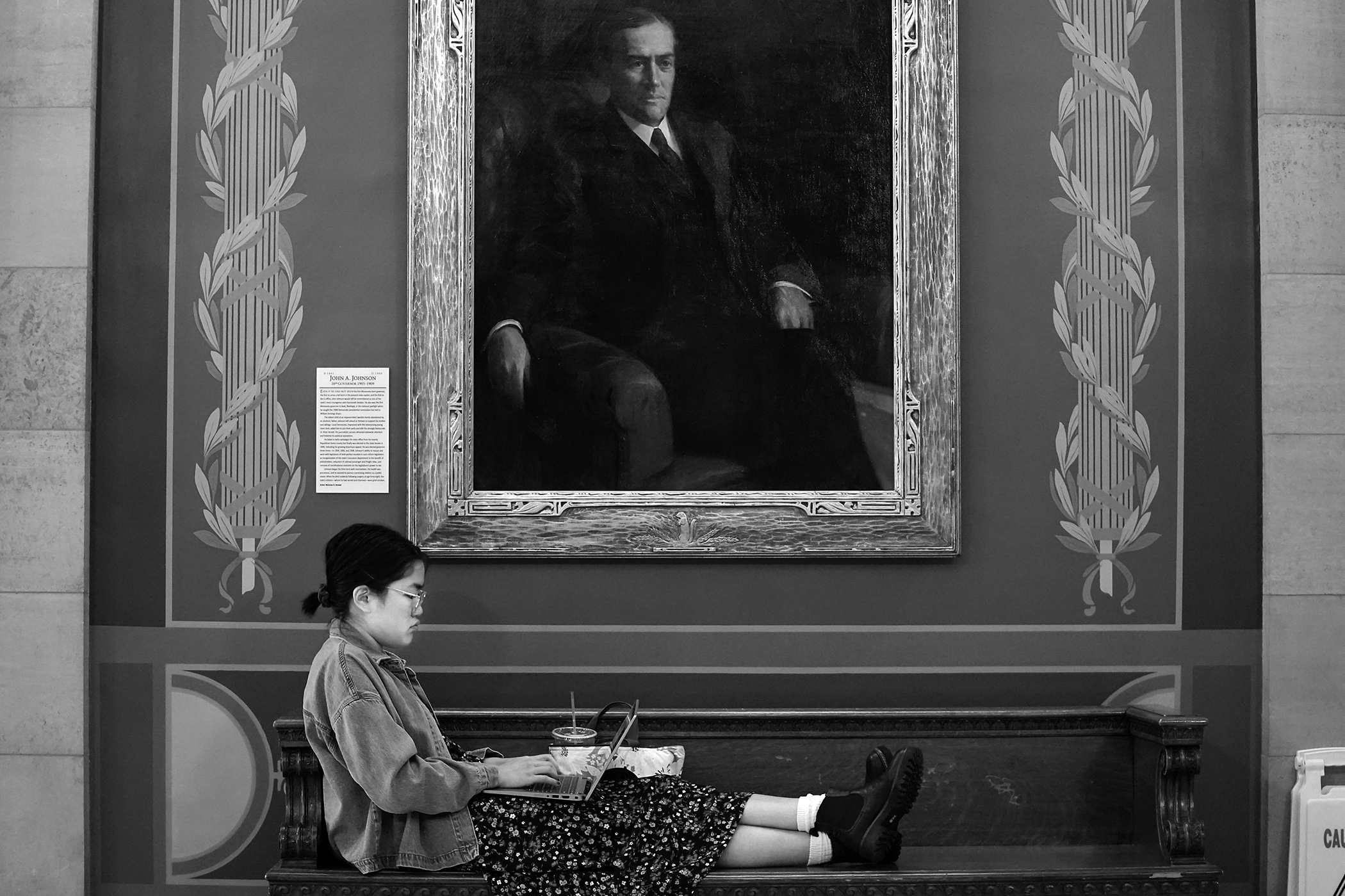Ceil Maus-Conn takes advantage of a quiet Capitol corridor to get some work done May 7 below the portrait of John A. Johnson, Minnesota's 16th governor. (Photo by Michele Jokinen)